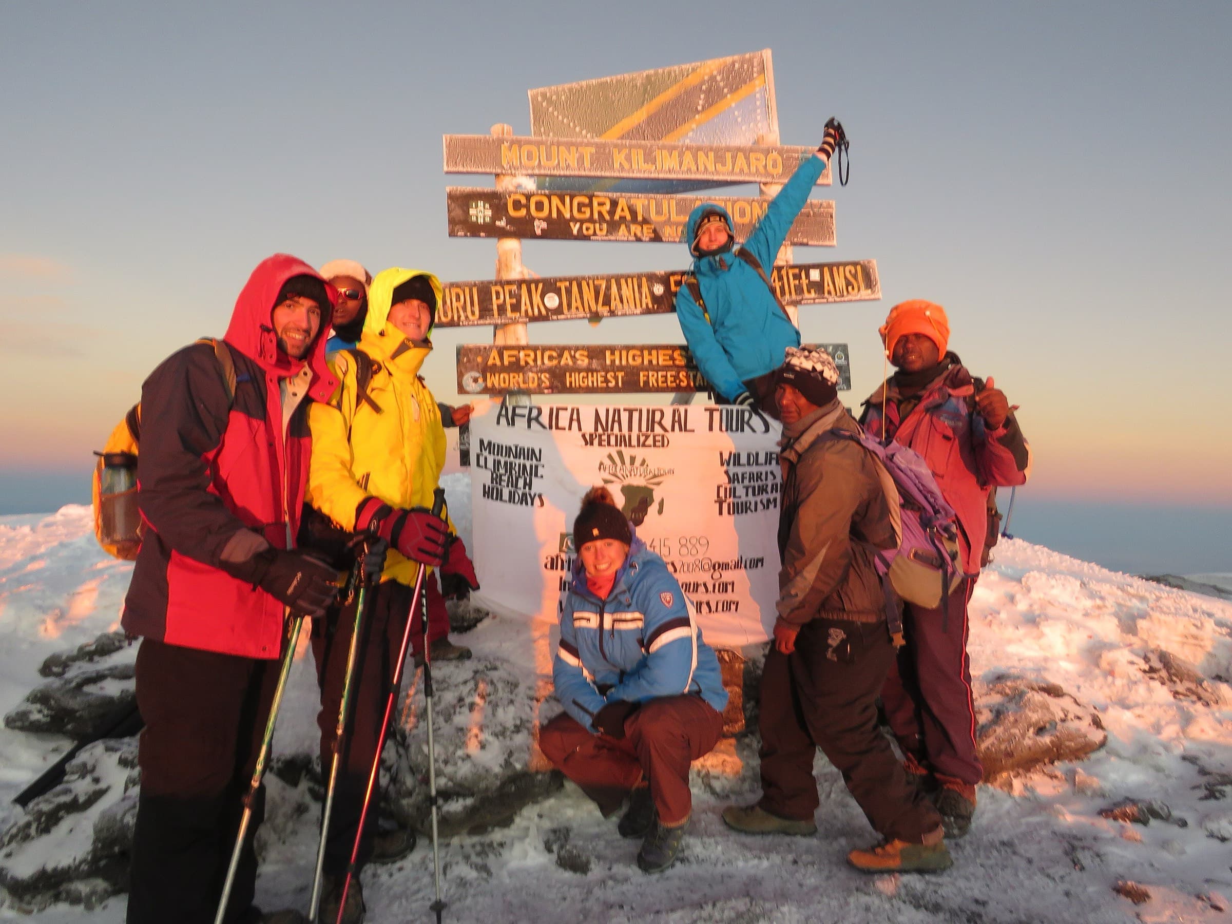 A climbing team and crew at the Uhuru Peak summit sign