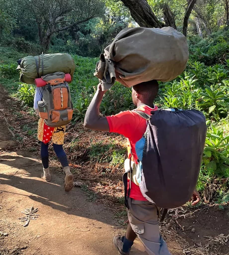 Porters carrying loads through forest on the Kilimanjaro trail