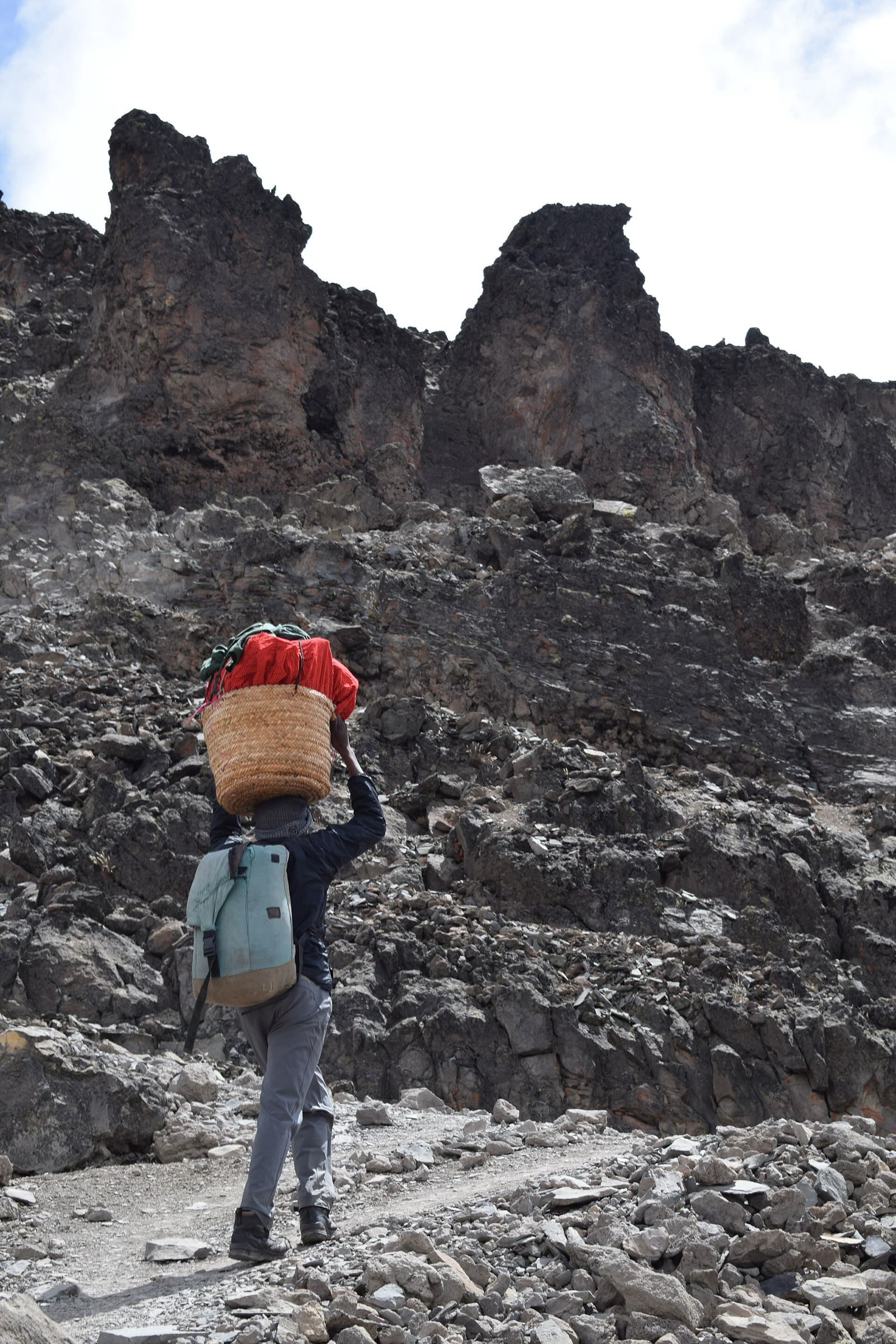 A porter on the trail with a rolled load balanced on the shoulder
