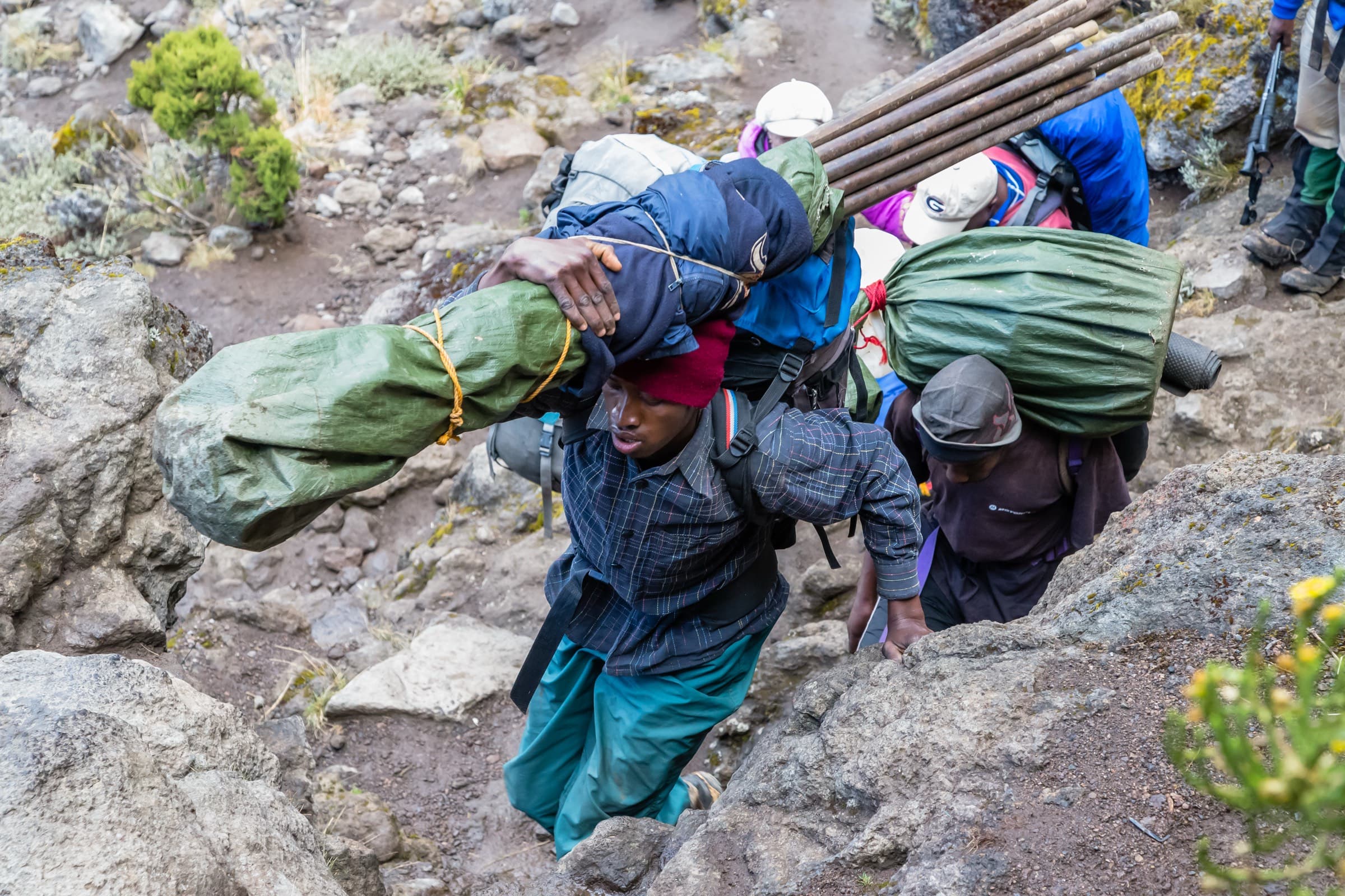 Porters shouldering large bundles at the base of the Barranco Wall